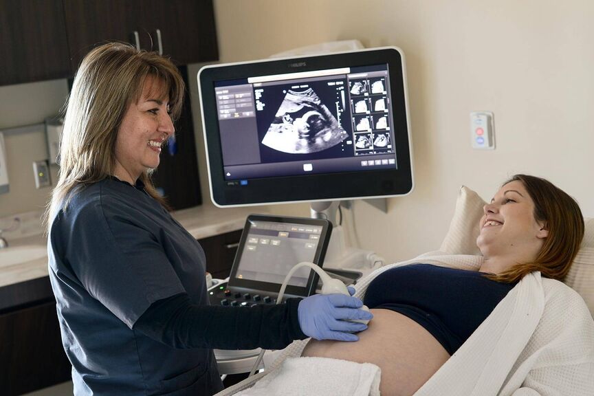 A sonographer performs a scan on a pregnant woman