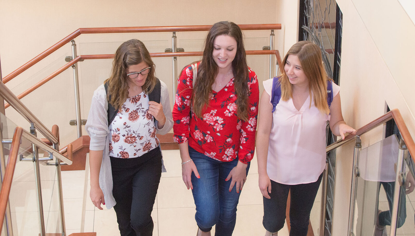 Three female students walking up the stairs together.