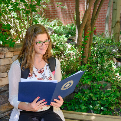 A female student studying reading outdoors