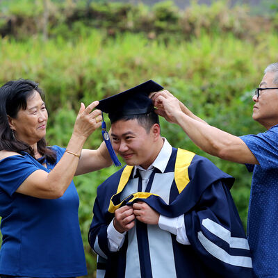 Parents help a graduate get dressed in cap and gown