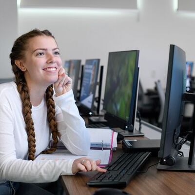 student looking at computer and smiling