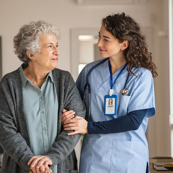A health care worker assists and elderly patient