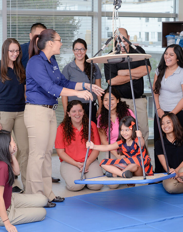 An occupational therapy faculty member demonstrating pediatric treatment to a group of students
