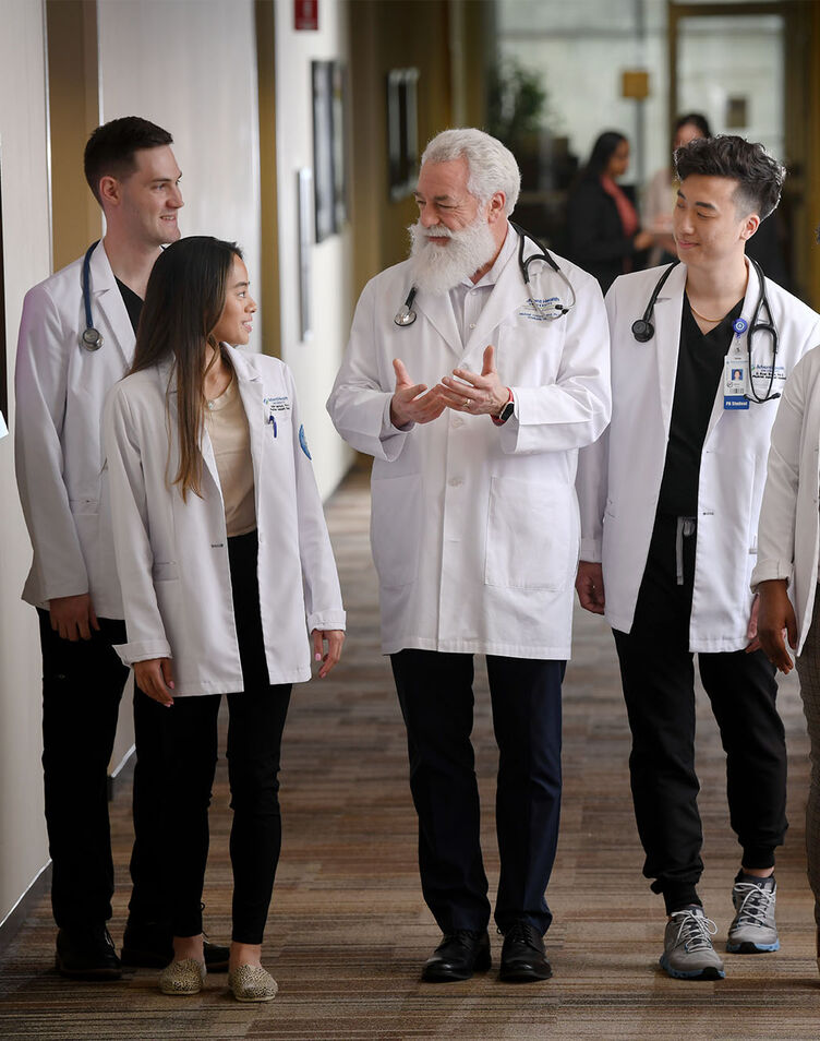 Physician assistant students walk down the hall with a faculty member
